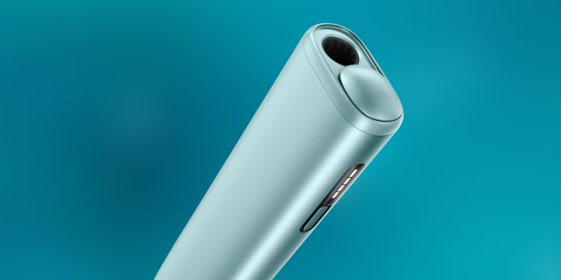 Green IQOS ILUMA i device and its charger on a light turquoise background